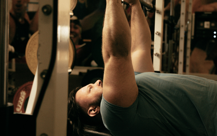Close up shot, Ben Wright lifting weights as part of the Just Add Venue brand campaign Close up photo of Ben Wright bench pressing weights as part of the Just Add Venue brand campaign